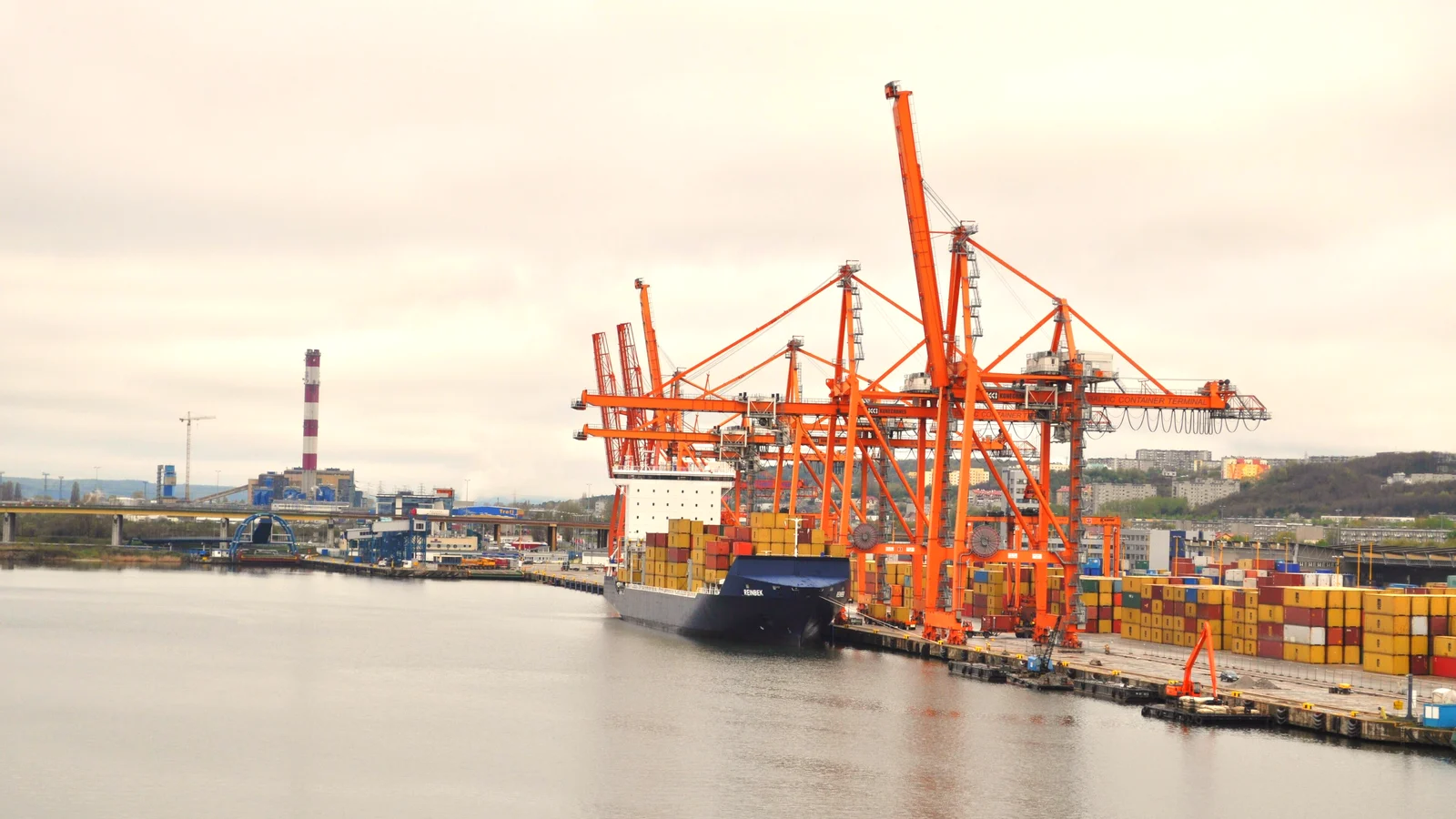 Container ship moored under orange gantry cranes at the port of Gdynia