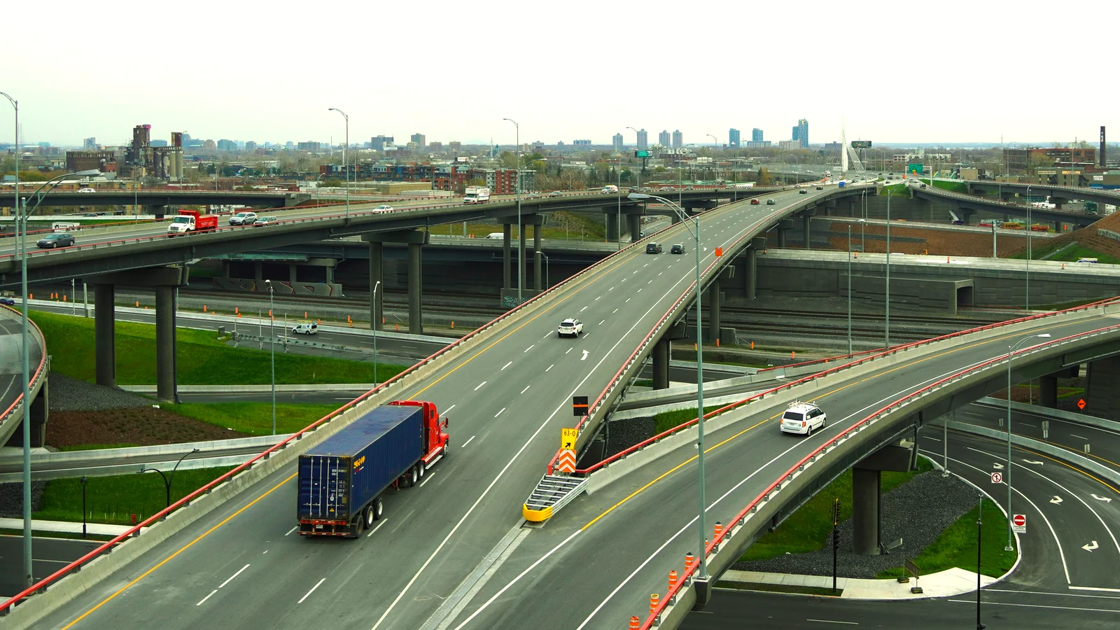 Semi truck on a highway interchange ramp above a city