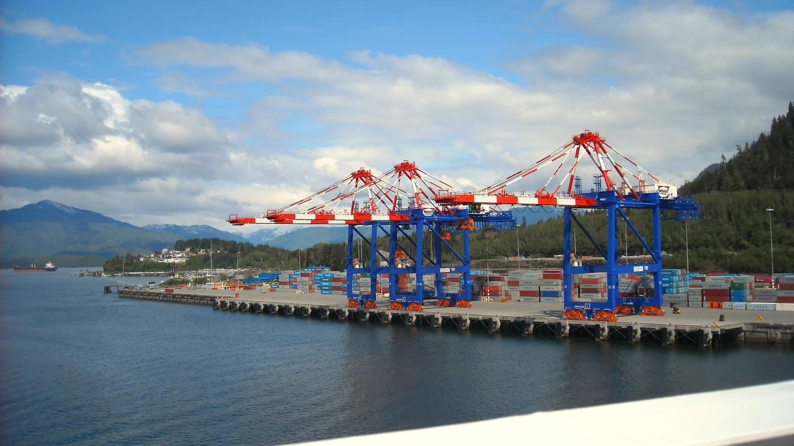 Gantry cranes along the container wharf at Prince Rupert with forested hills behind