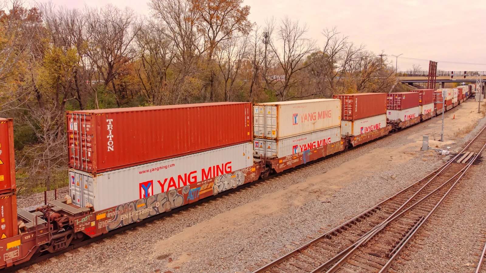 Double-stack intermodal train with red and white shipping containers on a rail line