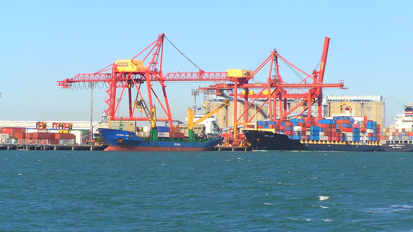 Container ships under red gantry cranes at Brisbane docks